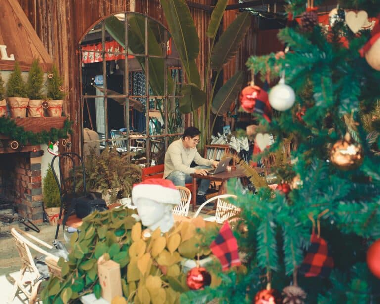 Man at work surrounded by holiday decorations.