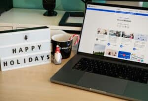 Office desk with laptop, happy holidays sign and a candy cane.