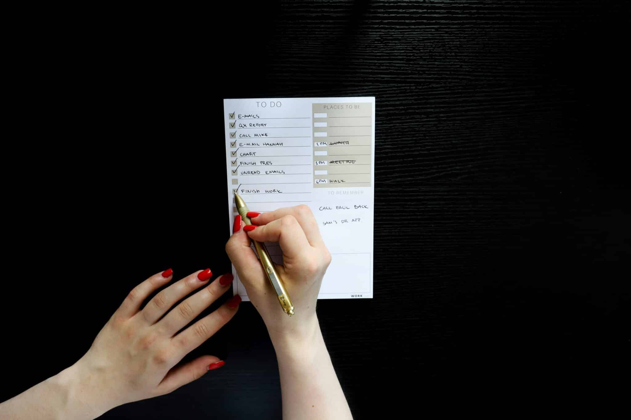 hand with bright red nails writing a checklist